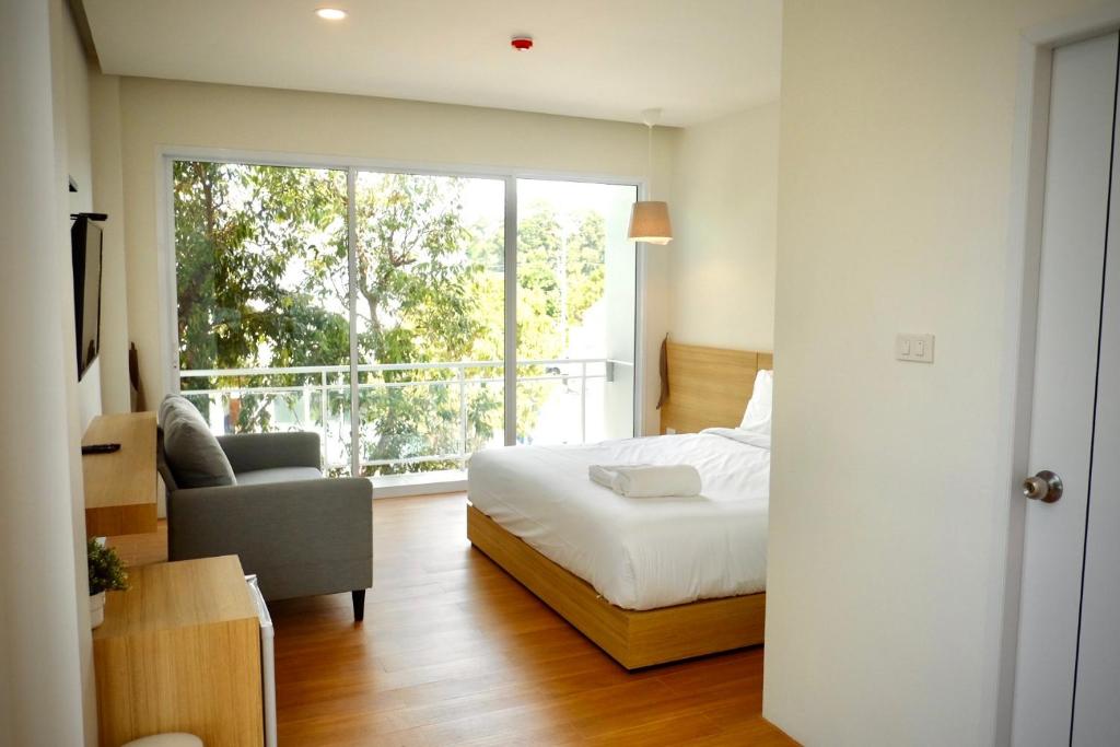 ein Schlafzimmer mit einem Bett und einem großen Fenster in der Unterkunft Busaba Bella Hotel in Sichon