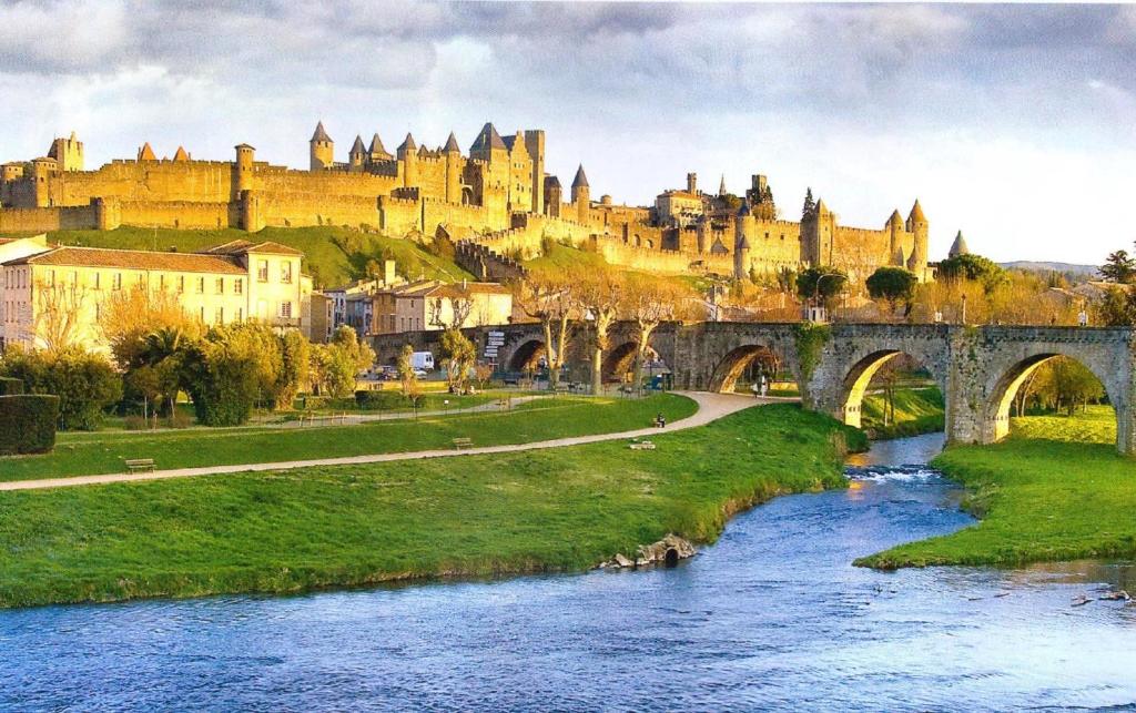 un pont sur une rivière en face d'un château dans l'établissement découvrez une ancienne maison de drapier du XVII siecle au coeur de bastide, à Carcassonne