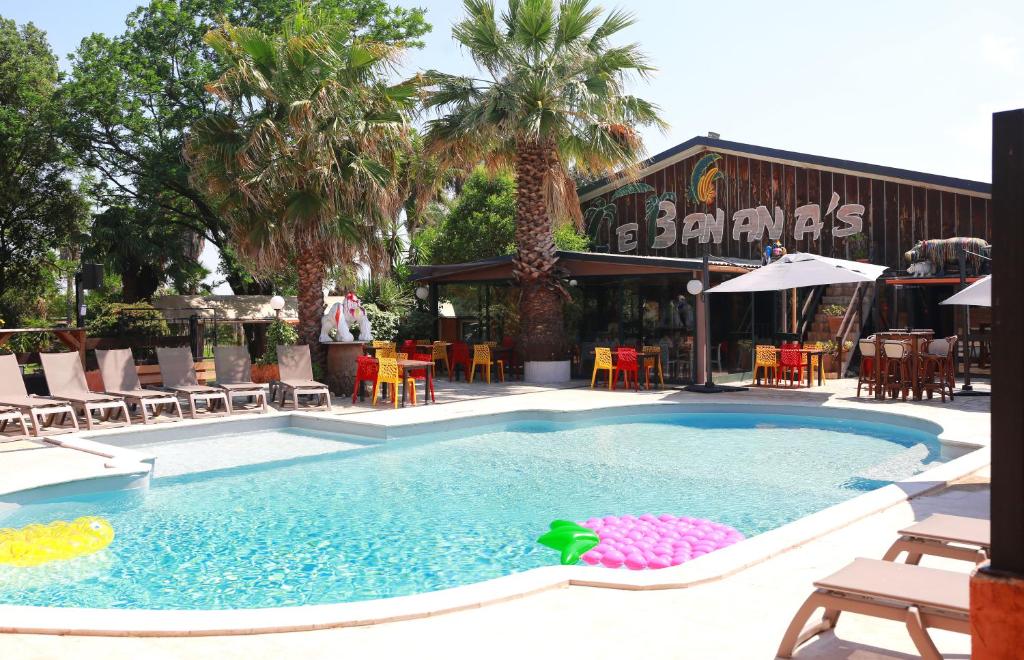 a swimming pool in front of a restaurant at Le Banana's Hotel in Aléria
