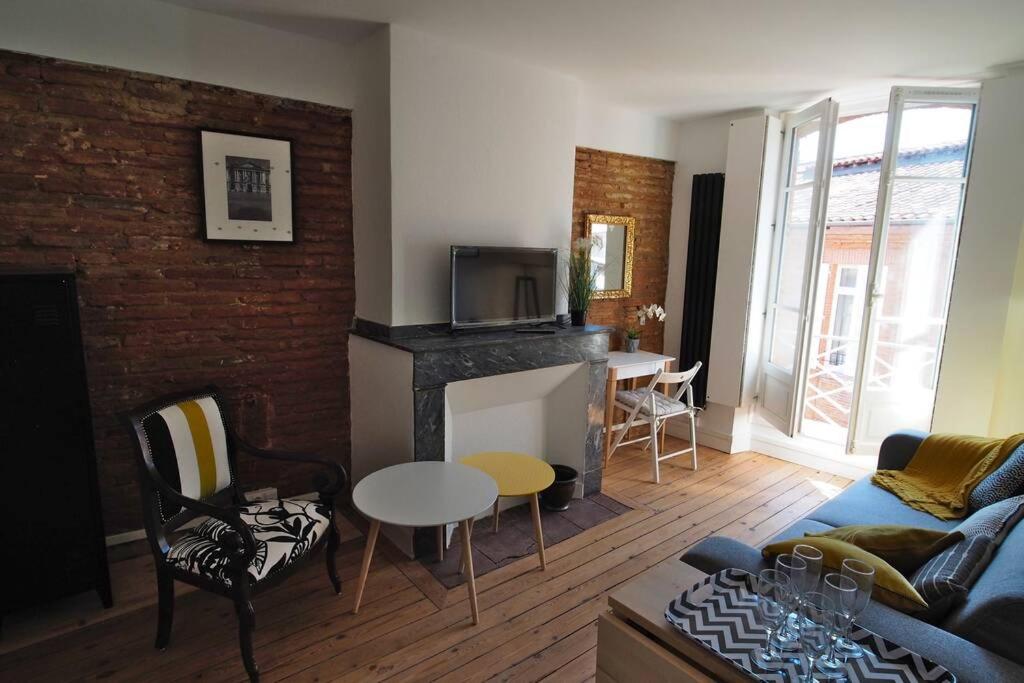 a living room with a couch and a fireplace at STUDIO BRICK AND WOOD - HYPERCENTRE - TV - WIFI in Toulouse