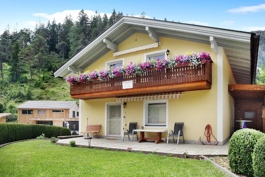 una casa gialla con balcone fiorito di Ferienwohnung Mark a Biberwier