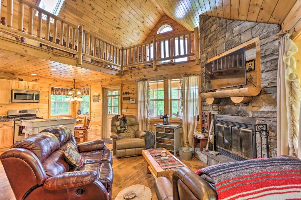 a living room with leather furniture and a stone fireplace at Charming Blakely Cabin with Porch and Valley Views! in Blakely