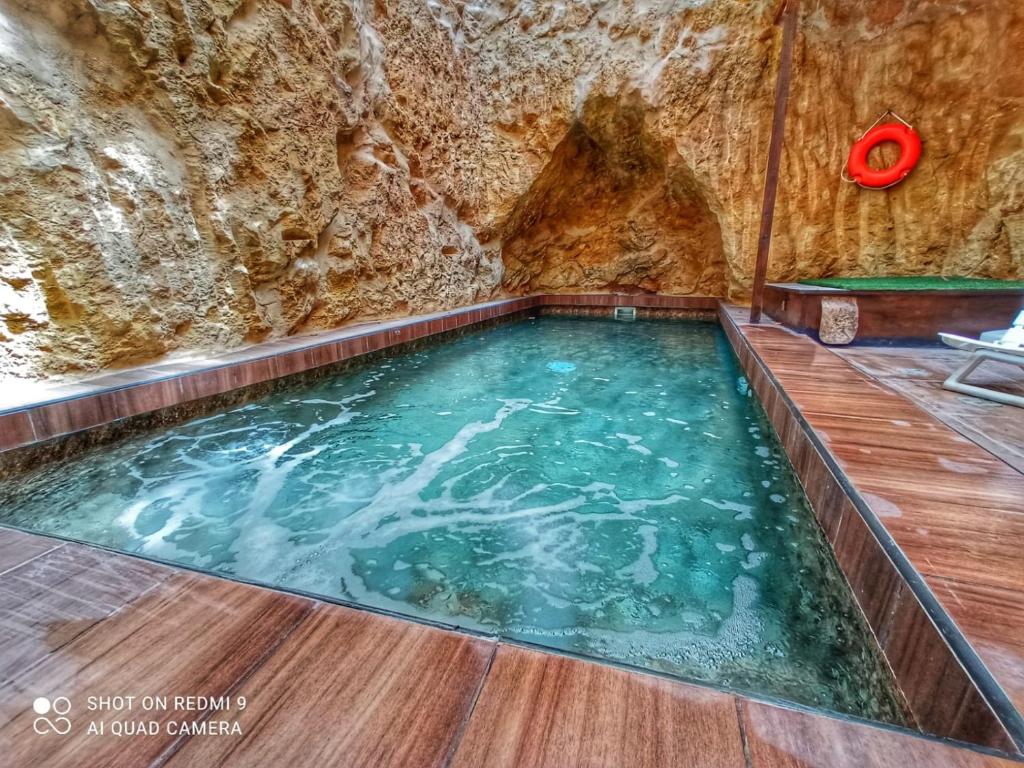 uma piscina numa caverna com uma parede de pedra em Town House with Private Pool in Village Centre em Kalkara