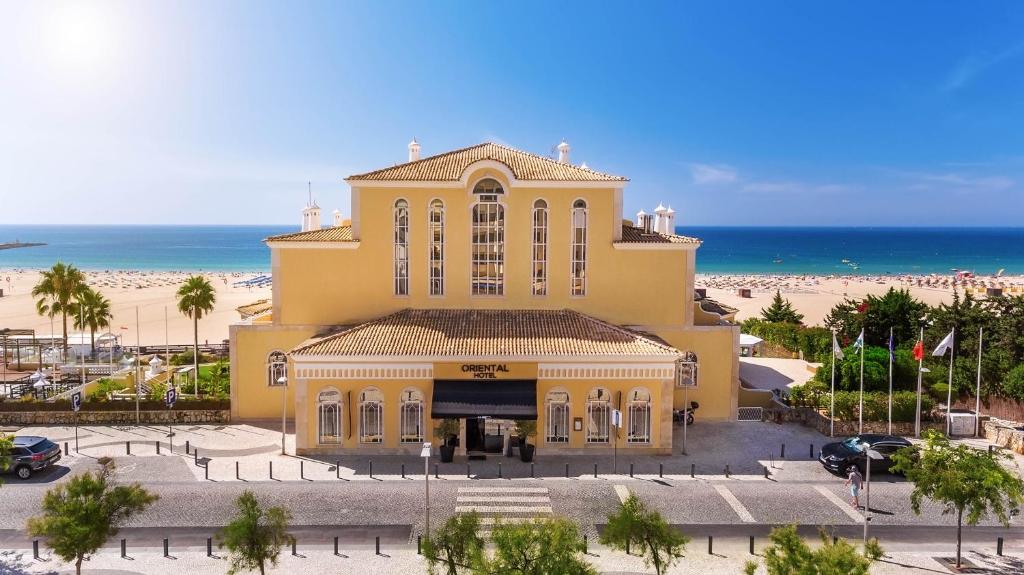a yellow building with the beach in the background at AP Oriental Beach - Adults Friendly in Portimão