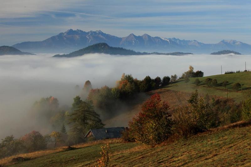 una casa en una colina en la niebla con montañas en Pod Wdżarem en Kluszkowce