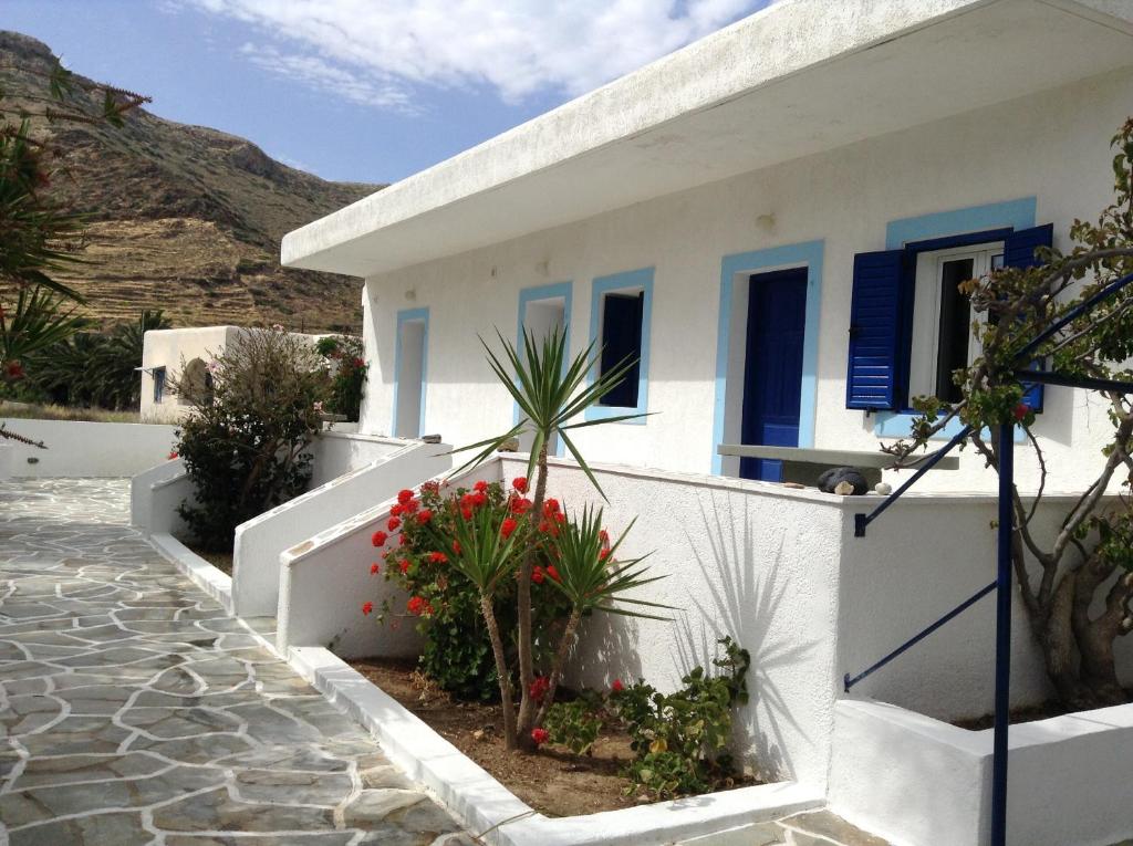 una casa blanca con ventanas azules y una planta en Oasis Apartments, en Ios Chora