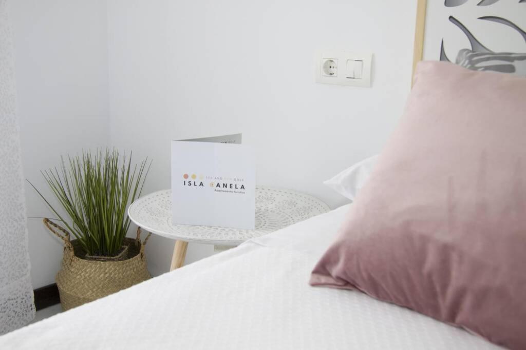 białe łóżko z różową poduszką i stołem w obiekcie Isla Canela Sea & Sun Golf - Ayamonte w mieście Ayamonte