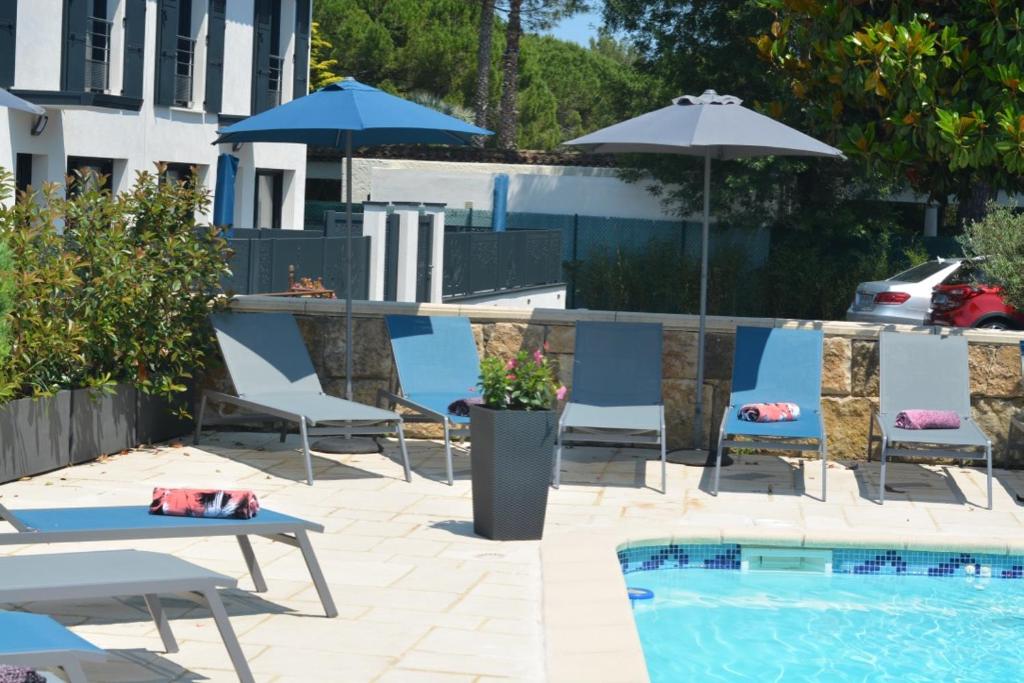 a swimming pool with chairs and umbrellas and a table and a pool at Les villas du Golf Mougins in Mougins