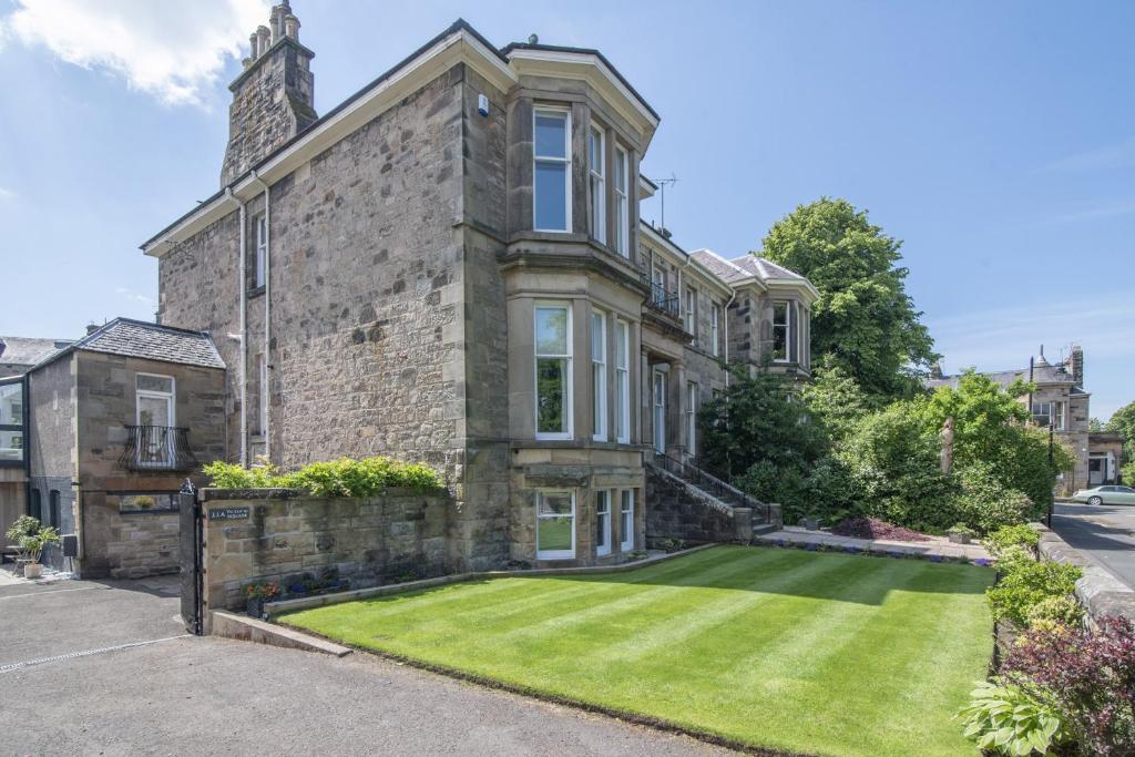 an old stone house with a lawn in front of it at Victoria Square in Stirling