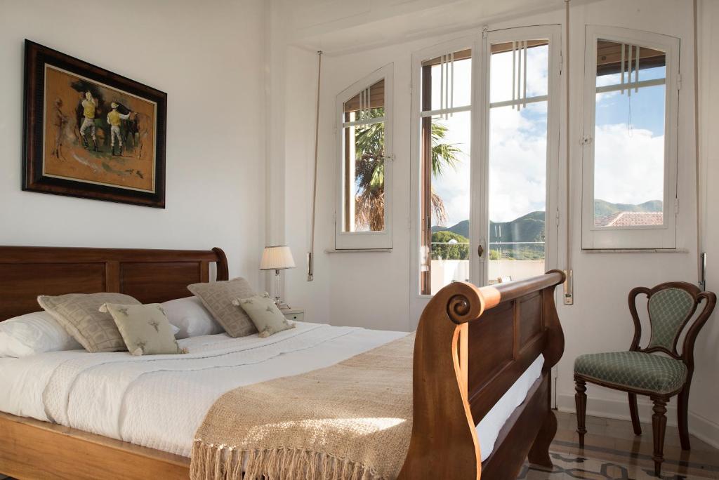 a bedroom with a bed and a chair and windows at Villa Inglese in Picinisco