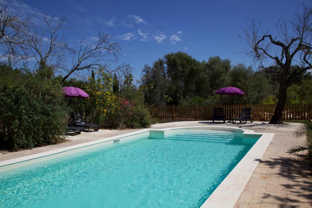 a swimming pool in a yard with two umbrellas at Villa Casa Rosa in Olhão