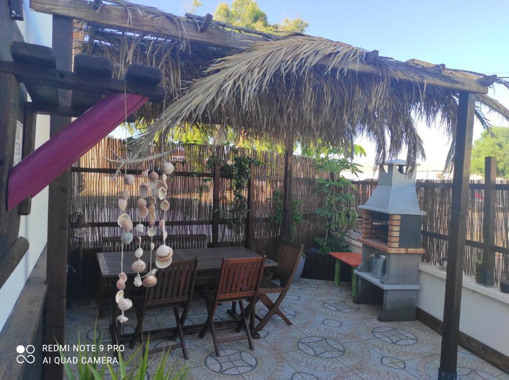 a patio with a table and chairs under a straw umbrella at Cortijo Los Flamencos in El Cabo de Gata