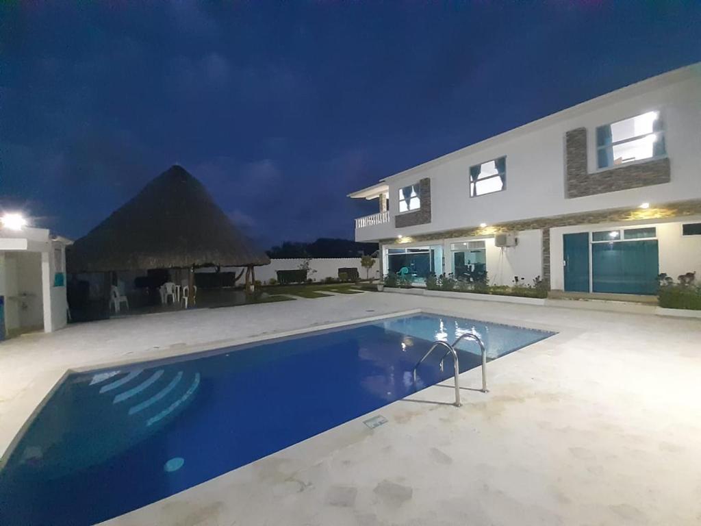una piscina frente a una casa por la noche en Cabaña Villa Carmen en Juan de Acosta