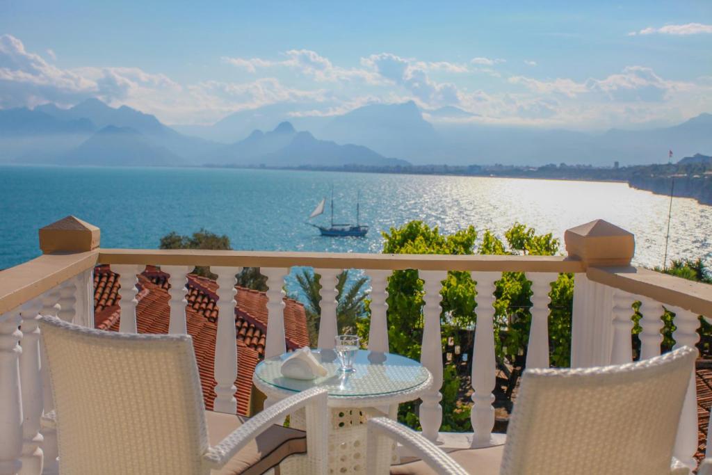 einen Tisch und Stühle auf einem Balkon mit Blick auf das Wasser in der Unterkunft Bacchus Pension in Antalya