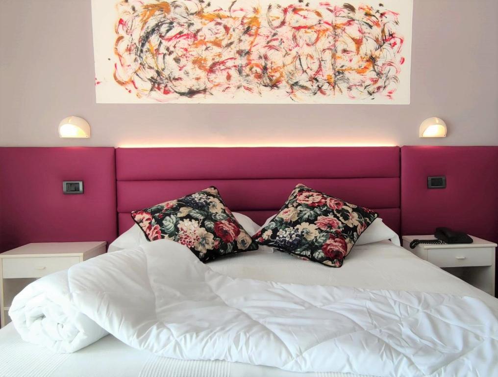 un letto con due cuscini e un dipinto sul muro di Hotel Villa Platani a Riccione