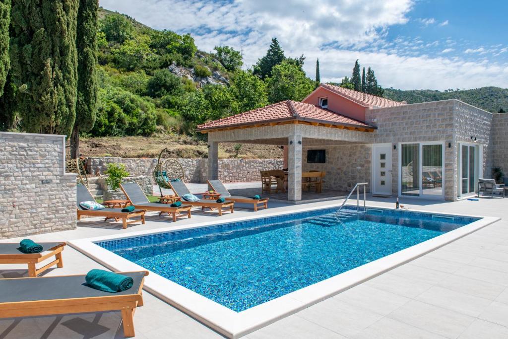 a swimming pool with chairs and a house at Villa Pajkan in Dubrovnik