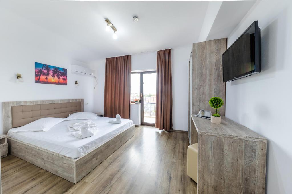 um quarto com uma cama e uma televisão de ecrã plano em Vila Yna em Mamaia Nord – Năvodari