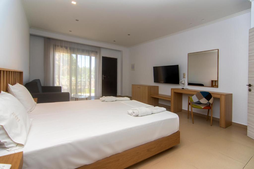 a bedroom with a large white bed and a television at Riviera Perdika Hotel in Perdika