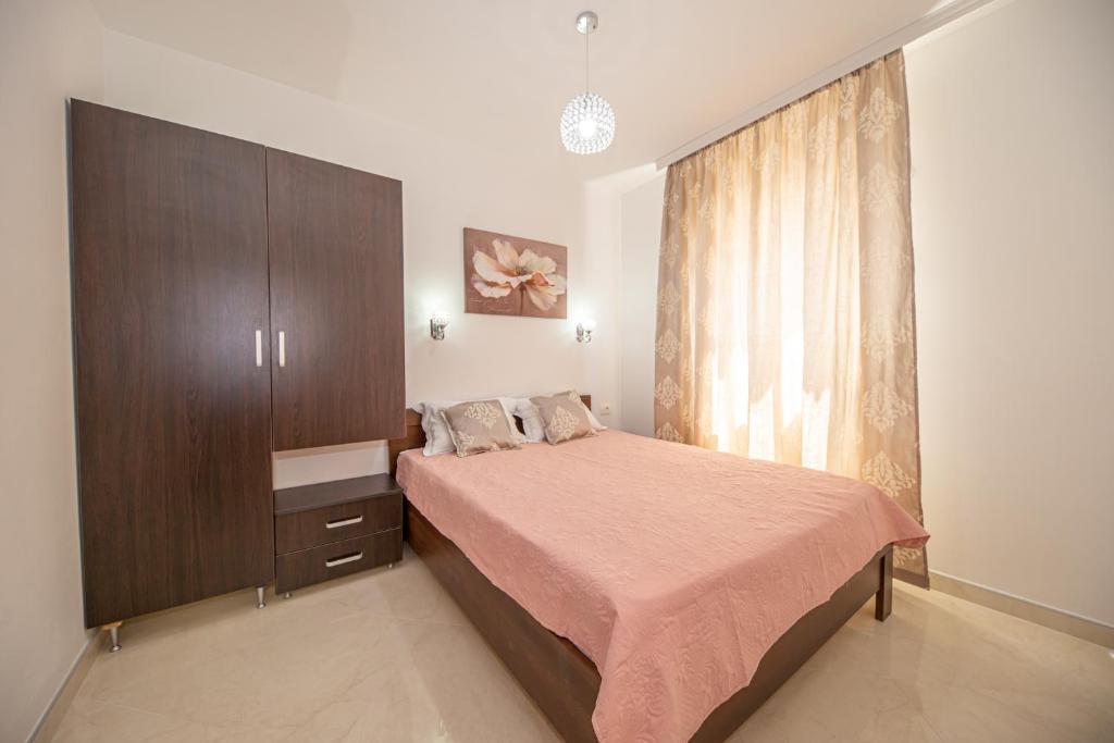 a bedroom with a bed and a cabinet and a window at Kristal Apartmani in Čanj