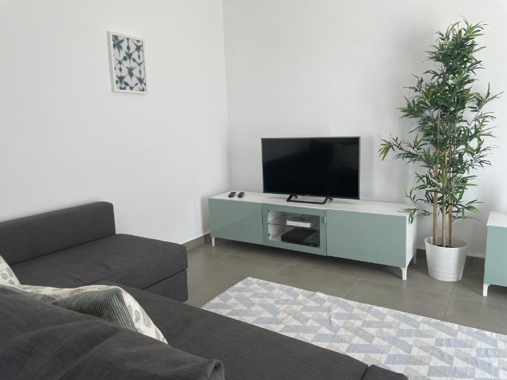 a living room with a couch and a tv at Vila Flor - Vilamoura in Vilamoura