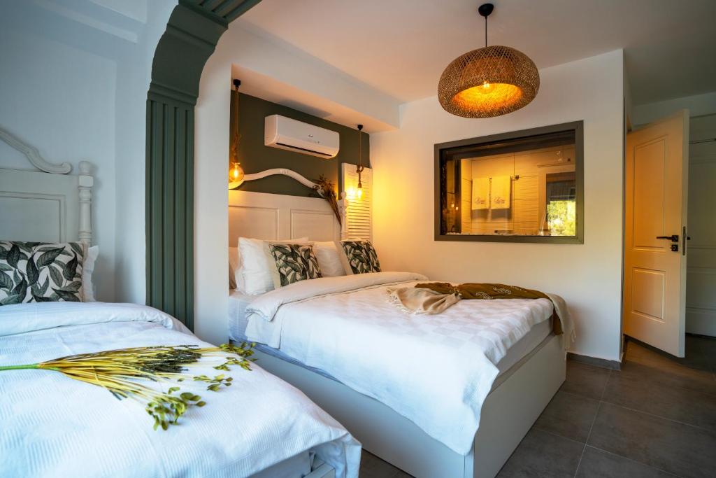 a bedroom with two beds and a mirror at Liman Hotel Gümüslük - Adult Only in Bodrum City