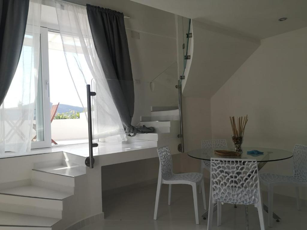 una cucina con tavolo, sedie e finestra di Casa Vacanze Le Palette - Glicine a Ponza