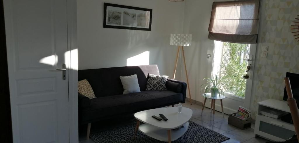 - un salon avec un canapé noir et une table dans l'établissement Maison de vacances cosy, à Avranches