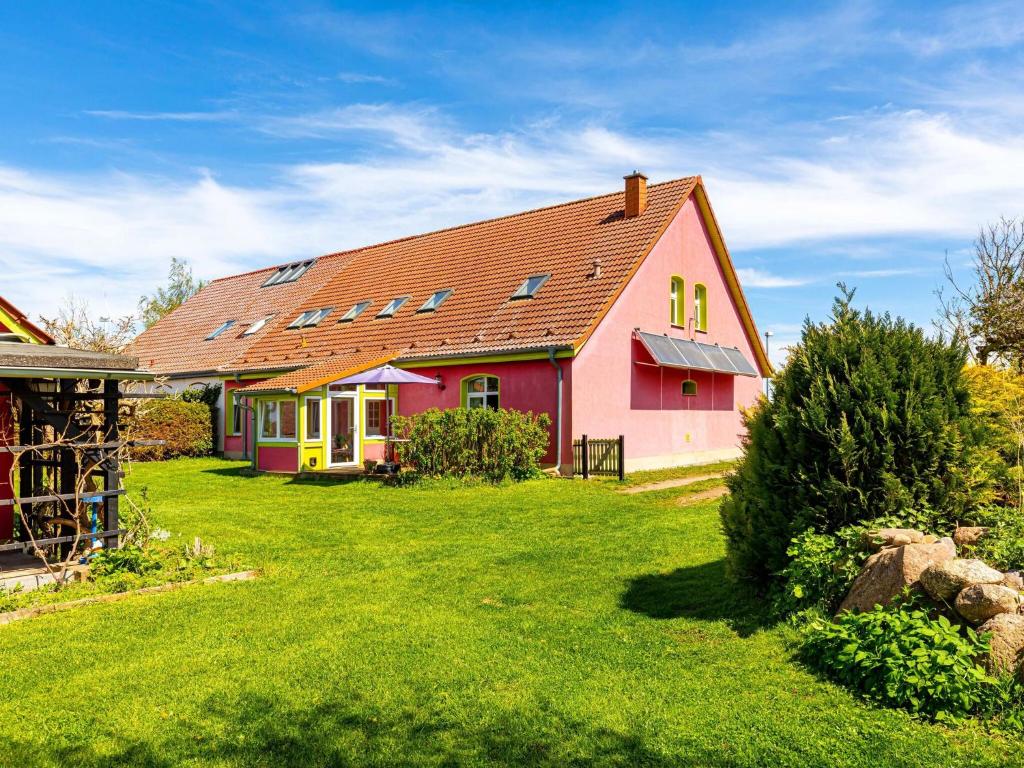 a red and pink house with a yard at Authentic and cosy holidayhome with big beautifull garden in Altentreptow