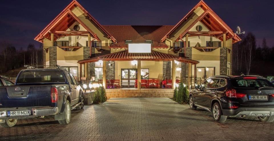 zwei nachts vor einem Haus geparkt in der Unterkunft Aranykakas étterem és panzió in Sîndominic