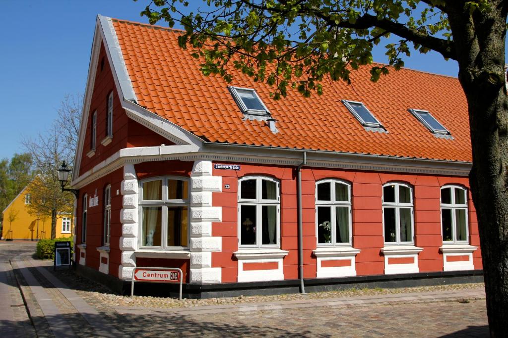 a red building with an orange roof on a street at Hotel Ribe in Ribe