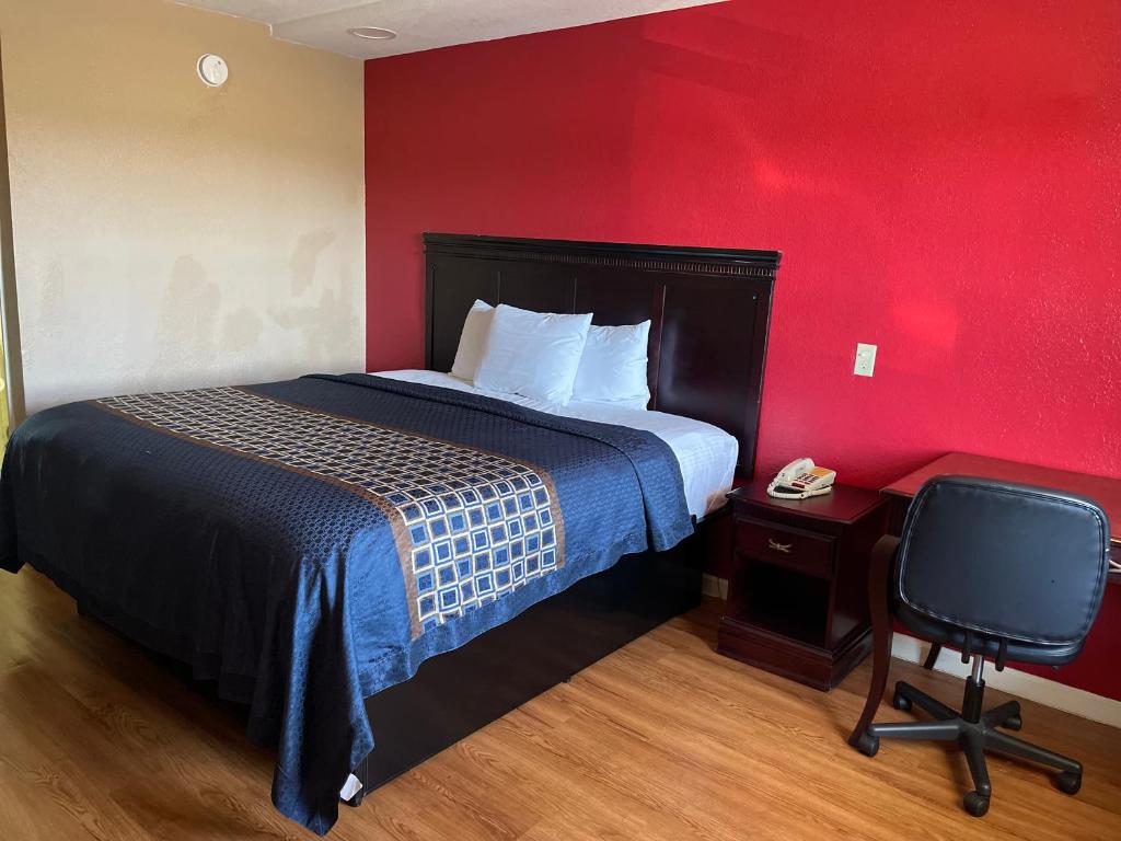 ein Hotelzimmer mit einem Bett und einem Stuhl in der Unterkunft Deluxe Inn in West Memphis