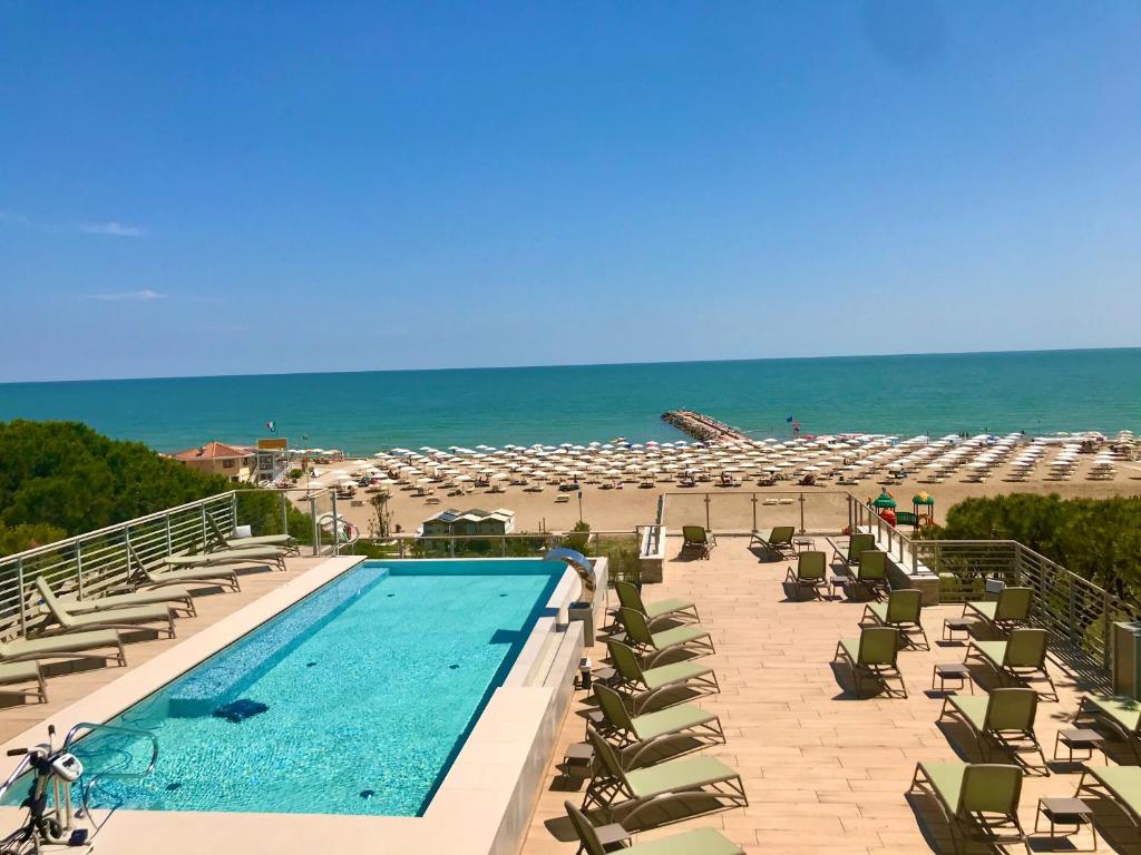 una piscina con sedie a sdraio e una spiaggia di Park Hotel Pineta & Dependance Suite a Eraclea Mare