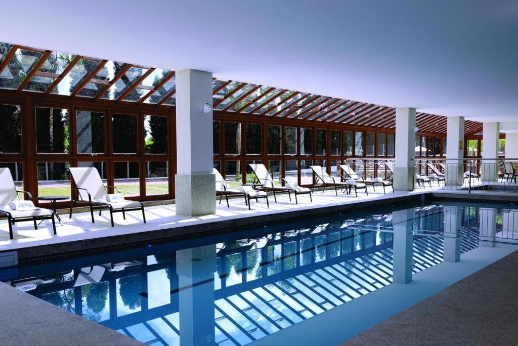 uma piscina com cadeiras e um edifício em Condomínio Vista Azul -CASA DOS CARDOSO em Domingos Martins