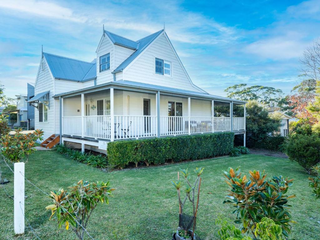 a white house with a large yard at Mermaid Cottage at Hyams Beach in Hyams Beach