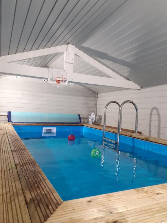 a indoor swimming pool with blue water and a basketball hoop at Gîte Le Bon Normand in Ã‰tainhus