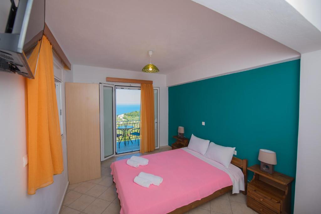 a bedroom with a pink bed and a balcony at Elena Studios in Athani
