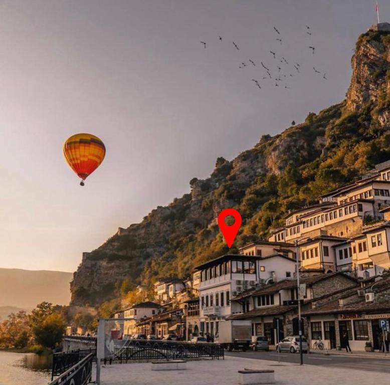 a couple of hot air balloons flying over a town at White House Berat in Berat