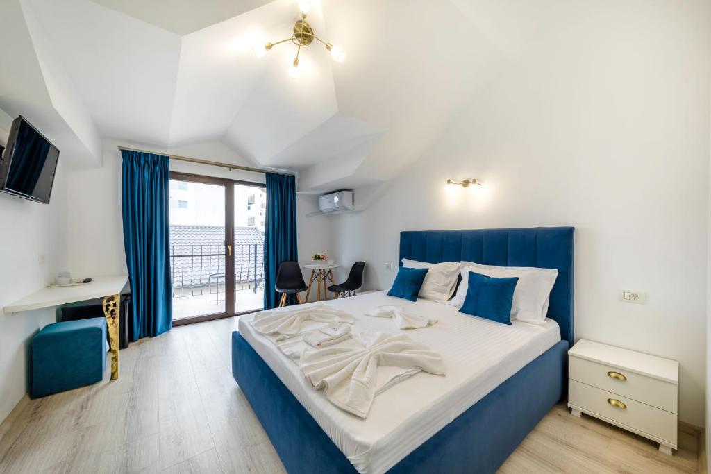 a bedroom with a blue and white bed and a window at Vila Kos in Mamaia Nord