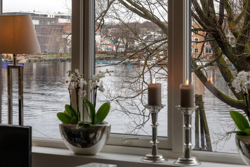 uma janela com duas velas e vista para a água em Stylish apartment with beautiful views of the river, beach nearby em Kristiansand