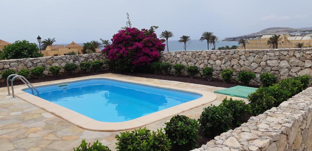 a swimming pool in front of a stone wall at Exclusive Villa Romeo mit privaten Pool, mit herlichen Panoramameerblik auf den Atlant in Costa Calma