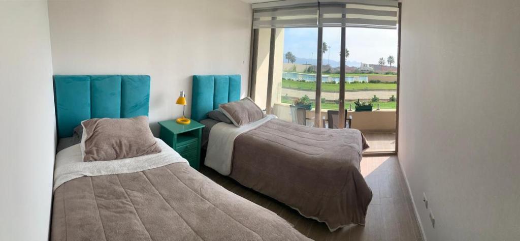 two beds in a room with a window at Bello departamento av del mar in Coquimbo