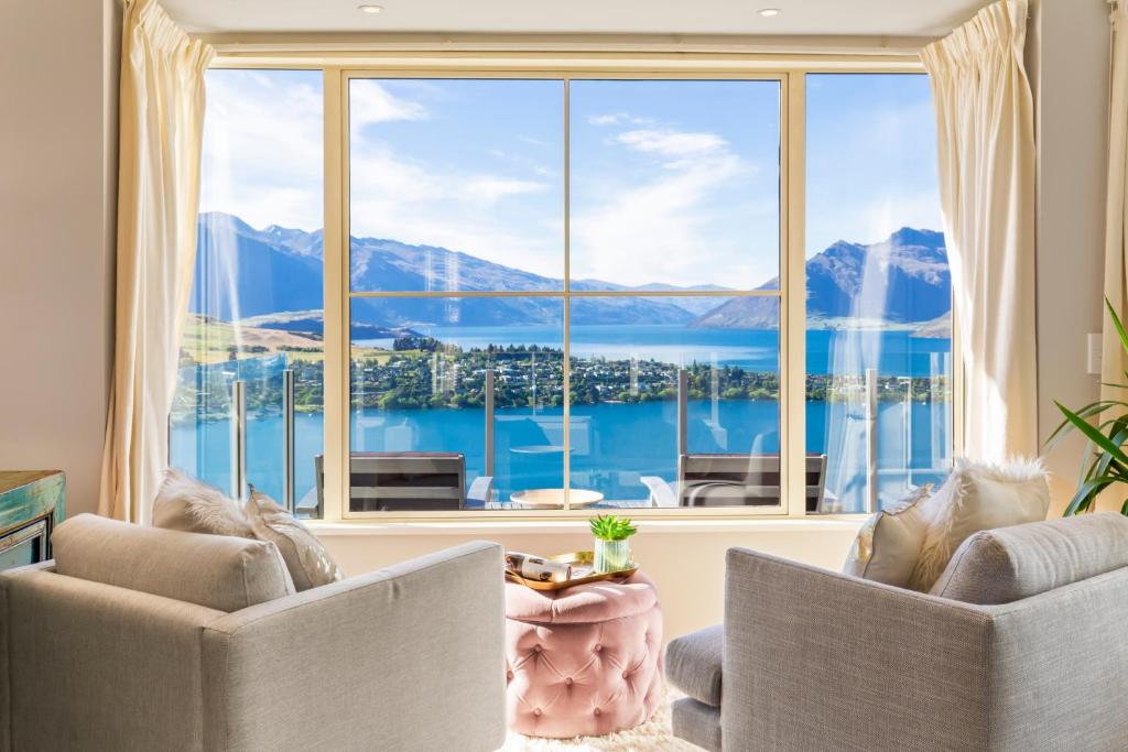 a living room with two chairs and a large window at Unbeatable Panoramic Lake & Mountain & Garden Views in Queenstown