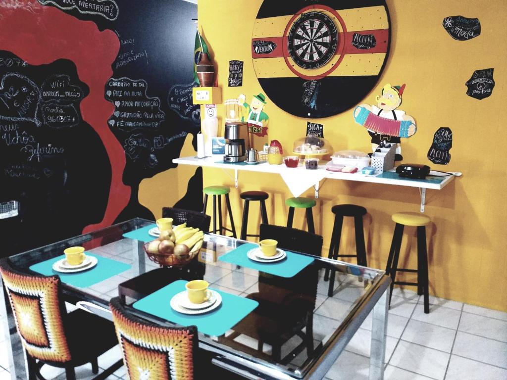 un restaurante con mesa y taburetes con tazas en Hostel Lumaria 1, en Blumenau