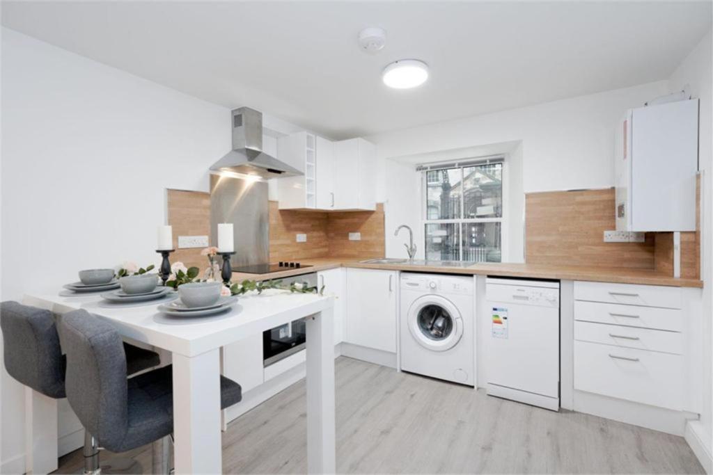 een witte keuken met een tafel en een wasmachine bij Royal Mile Old Town Apartment in Edinburgh