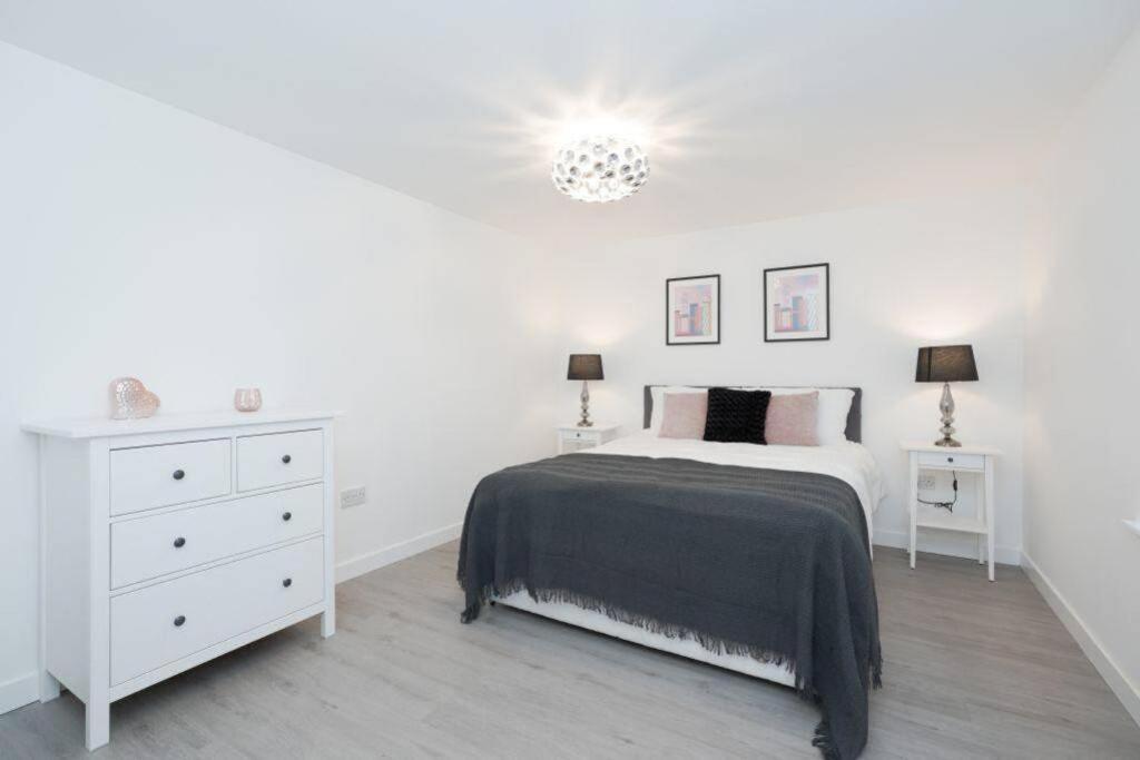 um quarto branco com uma cama e uma cómoda branca em Jewel of Royal Mile Apartment em Edimburgo