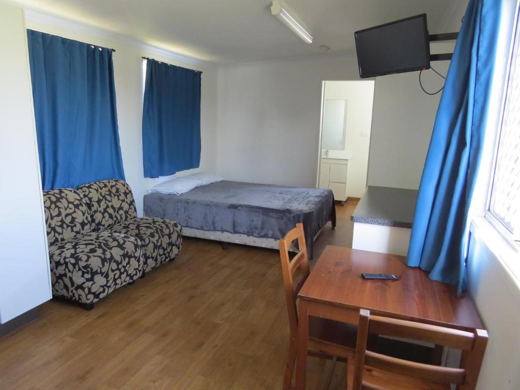1 dormitorio con 1 cama, 1 mesa y 1 silla en Bundaberg East Cabin and Tourist Park, en Bundaberg