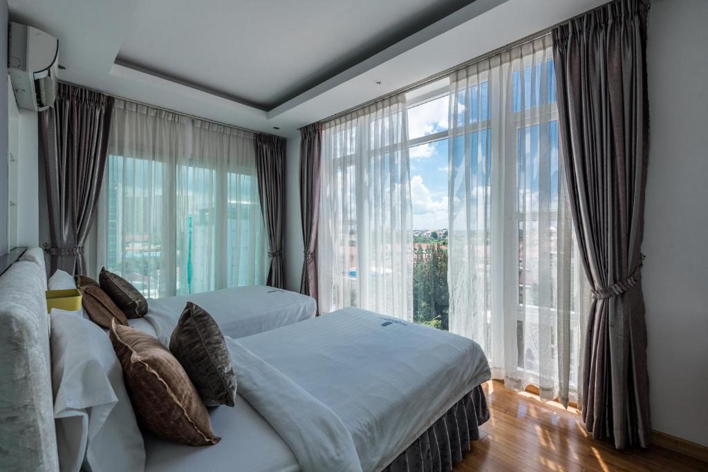 a bedroom with two beds and a large window at Naki Suites @ Silvertown in Phnom Penh