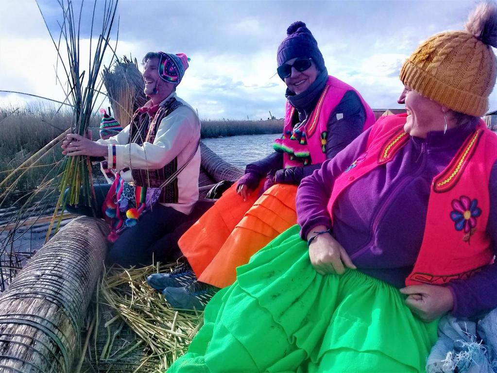 a group of women sitting on a boat in the water at Titicaca Habitación panorámica vista al amanecer in Puno