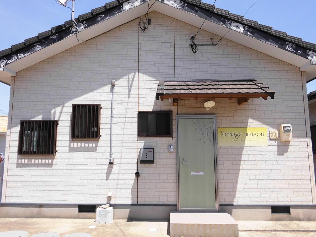 un edificio de ladrillo blanco con una puerta verde en Private House Mariage maison, en Goto