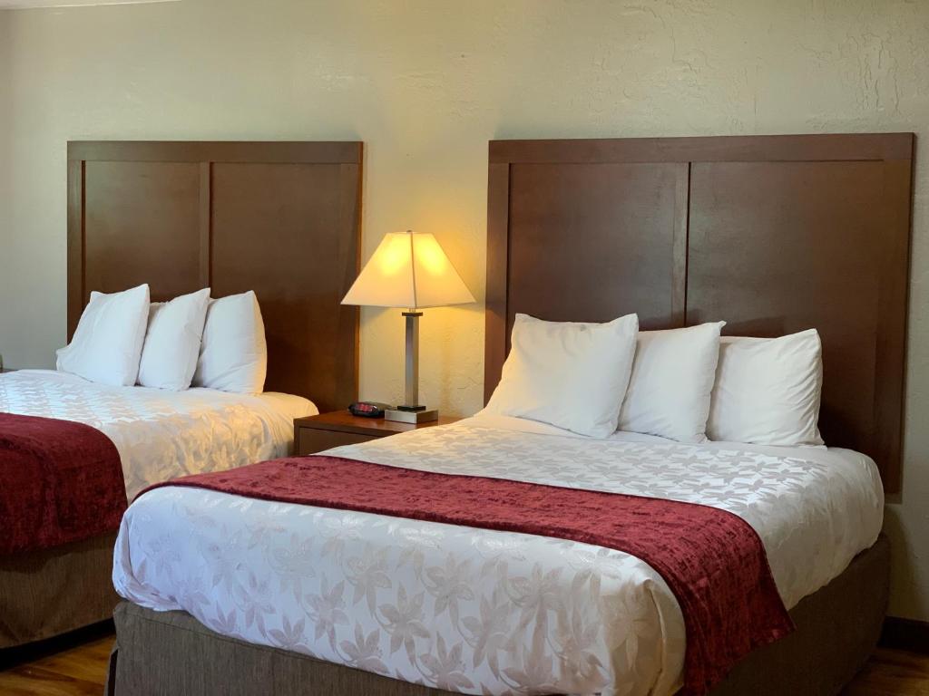 a hotel room with two beds and a lamp at Red Carpet Inn Medford in Medford